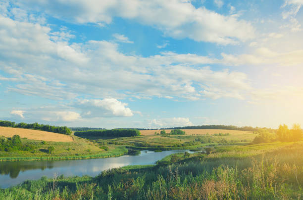 istock Sunny summer landscape with river,fields,green hills and beautiful clouds in blue sky. 1028195146