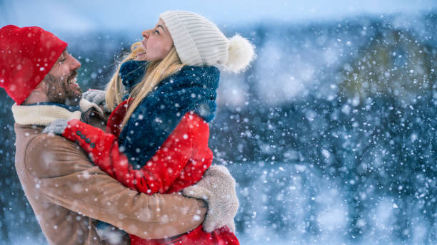 hübscher junge paar umarmen und glücklich lächeln, schnee fällt auf sie. paar in der liebe auf der hinterhof of their idyllischen home einen schönen wintertag. - couple winter expressing positivity loving stock-fotos und bilder