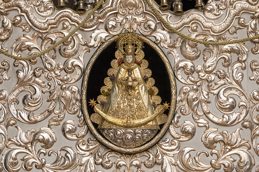 Close up of the statue of Holy Virgin Mary during the pilgrimage (Romeria) in El Rocio, Spain. About 100 different groups participate in this pilgrimage. Many of them have a cart with a small statue of Mary. The cart is richly decorated with flowers, (silver) candles and art work.
