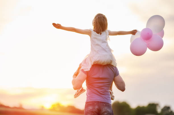 Happy loving family. Father and his daughter child playing and hugging outdoors. Cute little girl and daddy with air balloons.
