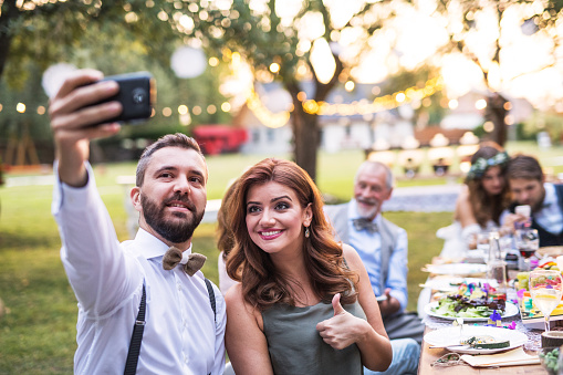 Una toma de pareja selfie en la recepción de la boda fuera en el patio trasero. photo