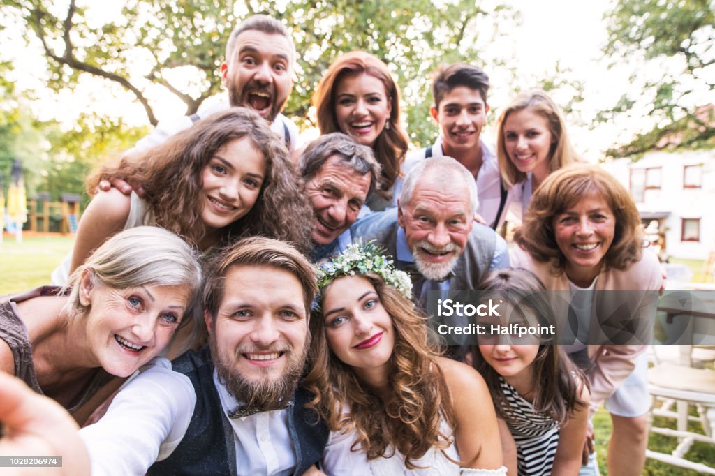 Bride, groom with guests taking selfie at wedding reception outside in the backyard. A close-up of happy bride, groom with guests taking selfie at wedding reception outside in the backyard. Wedding Stock Photo