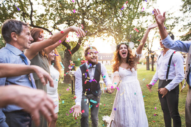 istock Bride, groom and guests throwing confetti at wedding reception outside. 1028207034