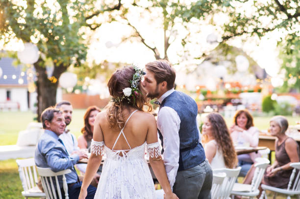 невеста и жених целуются на свадебном приеме снаружи на заднем дворе. - wedding reception wine party women стоковые фото и изображения