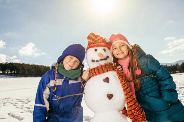 istock Boy and girl making snowman 1028212446