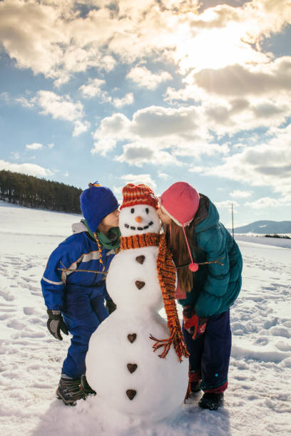 istock Boy and girl making snowman 1028212754