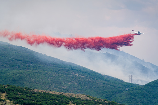 Airplane Releasing Red Fire Retardent Firefighting Wildfires. Basalt Wildfire - destructive fire summer 2018 near Aspen, Colorado USA. Forest fire during extreme conditions.