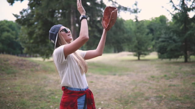 Gorgeous girl with a baseball glove playing baseball in nature