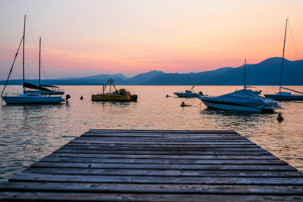 ガルダ湖、イタリアの海岸の背景にモーター ボートのイメージ - lake garda sunset blue nautical vessel ストックフォトと画像