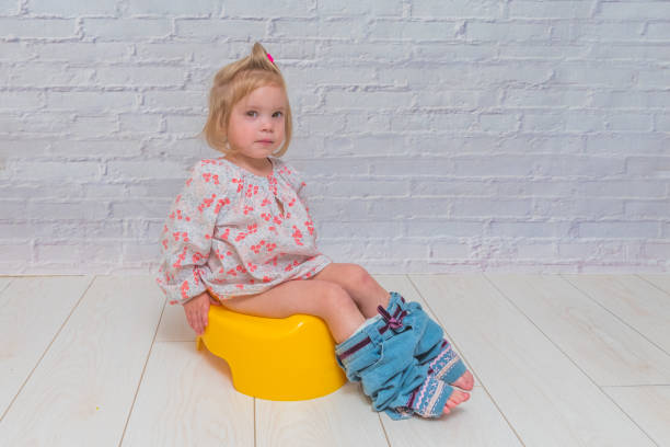 a girl, baby sitting on a potty on a white brick wall background girl, baby sitting on a potty on a white brick wall background accustom stock pictures, royalty-free photos & images