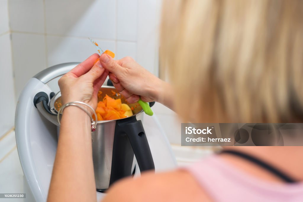 mujer de las manos preparación de puré de calabaza en cocina máquina - Foto de stock de Robot libre de derechos