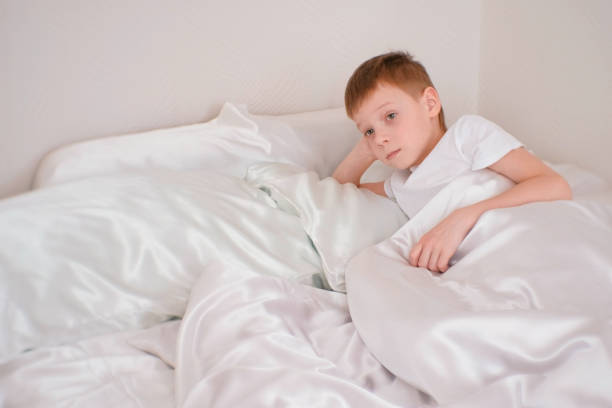 istock Seven-year-old boy wakes up in his bed under the blanket 1028264014