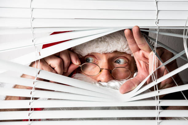 santa clause peeks through a window blind - burglary thief fear burglar imagens e fotografias de stock