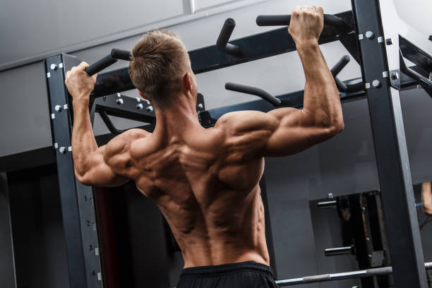Muscular man training his back Muscular man training his back in gym pullups ripl fitness