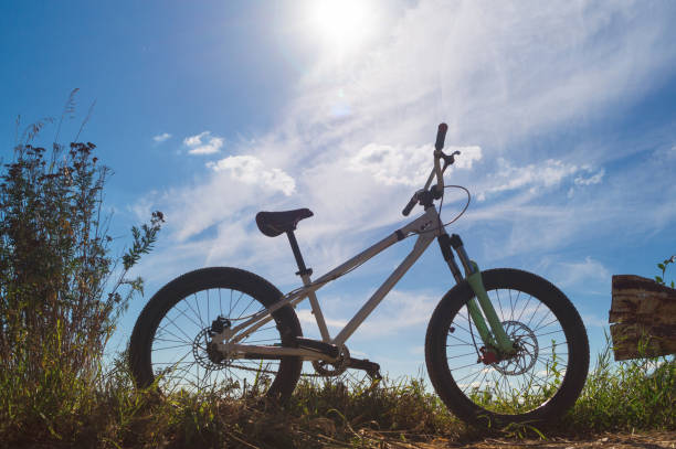 White bicycle at the rural roadside against a sunny blue sky with clouds