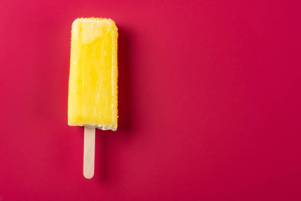 istock yellow popsicle on a rose red background 1028280826