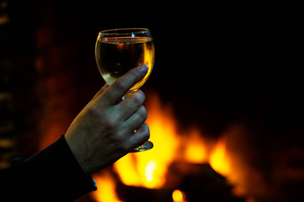 istock Hand holds wine glass in front of fire 1028290548