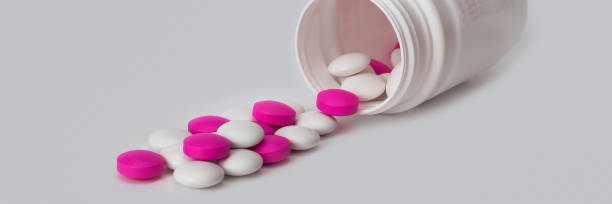 istock White and white tablets scatter from the white plastic bottle. Side view. Close-up. 1028291144