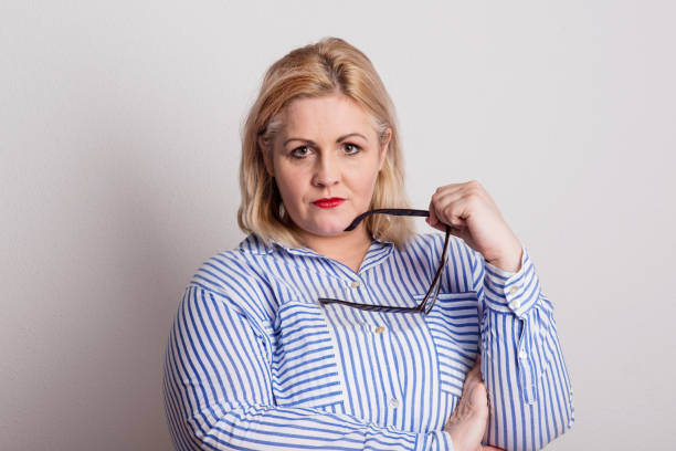 Portrait of an attractive overweight woman with glasses in a studio. Portrait of an attractive blond overweight woman with red lips and glasses in studio on a white background. big fat lips stock pictures, royalty-free photos & images
