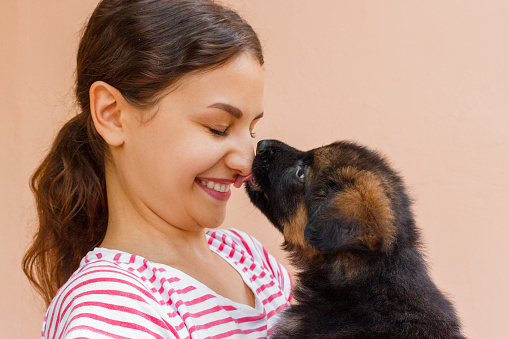 True friendship between girl and puppy who is giving a kiss.