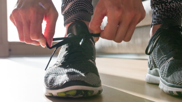 Woman tightening the knot on her sports shoe, getting ready for morning run