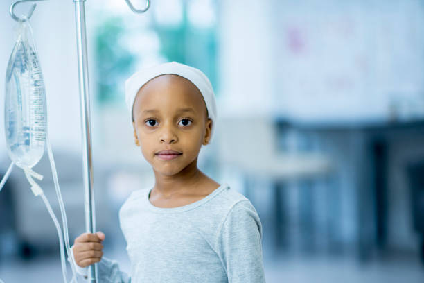 Cancer Patient A young girl with cancer is indoors in a hospital. She is holding her IV and staring at the camera. iv drip photos stock pictures, royalty-free photos & images