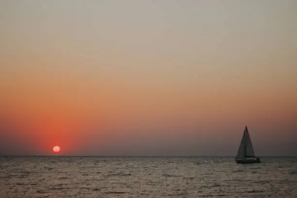 Lonely sailboat against the sunset at the sea