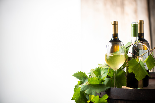 Glass of white wine on a barrel on white background