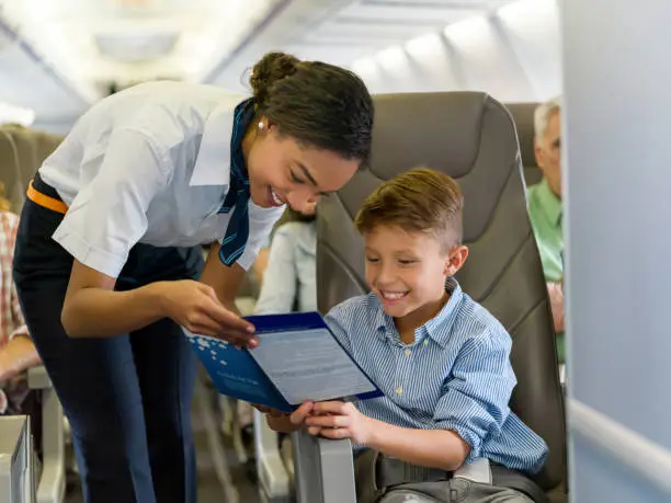 Portrait of a friendly flight attendant helping a boy in an airplane and looking very happy - travel concepts. **DESIGN ON COVER MAGAZINE WAS MADE FROM SCRATCH BY US**