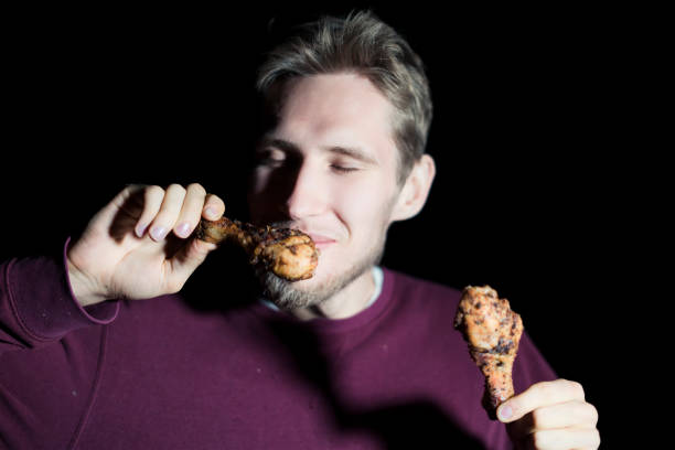 istock young bearded man eating fried chicken meat grill ham isolated on a dark background 1028372778