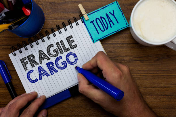 istock Text sign showing Fragile Cargo. Conceptual photo Breakable Handle with Care bubble pack Glass Hazardous Goods Man holding marker notebook clothespin reminder wooden table cup coffee 1028390872