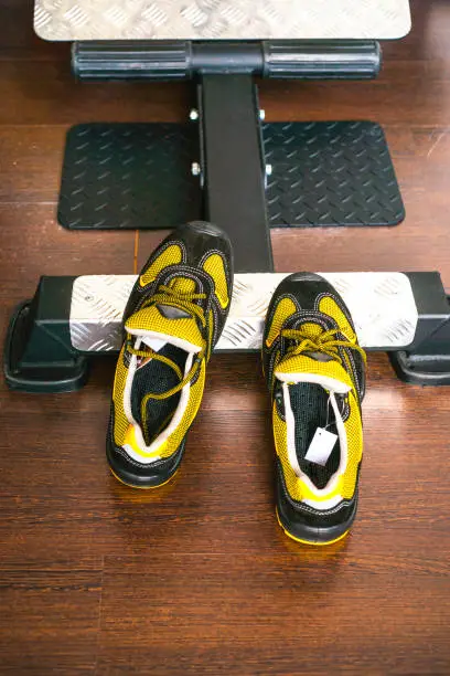 Unbranded modern sneaker in the gym. Black-Yellow. Comfortable shoes. Wearing sport shoes, doing wide step, demonstrating healthy way of life, wide shot. copy space for text.