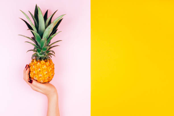 Hands with pineapple on stylish pink and yellow