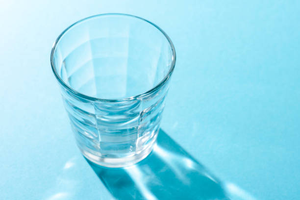 istock Transparent glass Cup on blue background and long shadow from it with different pictures 1028404462