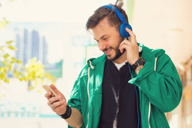 istock Stylish hipster man with headphones using phone 1028407412