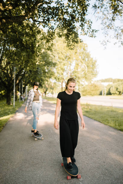 istock Two girls riding longboards down the path 1028411052