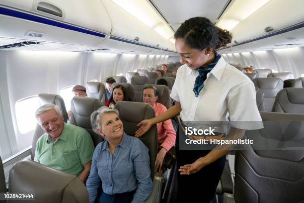 Flight Attendant Checking On A Senior Couple In An Airplane Stock Photo - Download Image Now