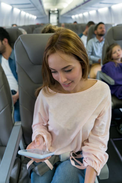 istock Woman traveling by plane and using her cell phone 1028421482