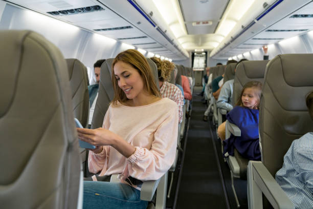 istock Beautiful woman using her cell phone on an airplane 1028421494