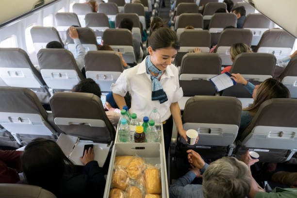 azafata que sirve comida y bebidas a bordo - aeromoza fotografías e imágenes de stock