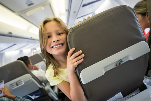 Portrait of a beautiful happy girl traveling by plane and looking at the camera smiling