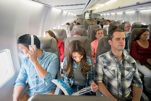 Happy group of Latin American people sitting onboard while traveling by plane - travel lifestyle concepts