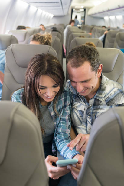 istock Happy couple traveling by plane and using their mobile phone onboard 1028421734