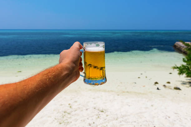 Cheers with a beer from a tropical beach