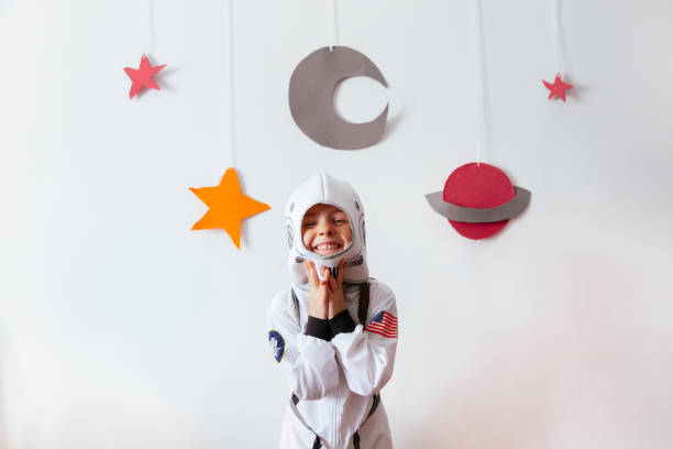 girl with an astronaut costume at home little girl with an astronaut costume at home science and technology kids stock pictures, royalty-free photos & images