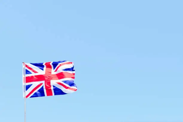 Union Jack flag of Great Britain UK Blowing in the wind against a empty blue sky uk