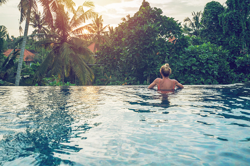 Young woman on the edge of an infinity pool, Ubud, Bali\nPeople travel vacations concept.