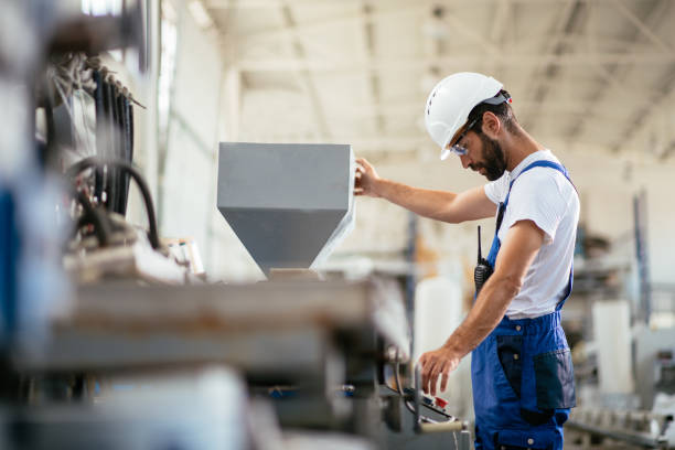 Worker in factory Worker in factory. Shadow DOF. Developed from RAW; retouched with special care and attention; Small amount of grain added for best final impression. 16 bit Adobe RGB color profile. machine stock pictures, royalty-free photos & images