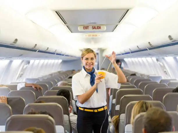 Portrait of a beautiful flight attendant making an in-flight safety demonstration and showing how to put the oxygen mask