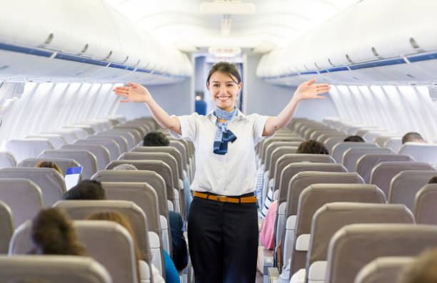 assistente di volo che mostra l'uscita di emergenza in un aereo - assistente di volo foto e immagini stock